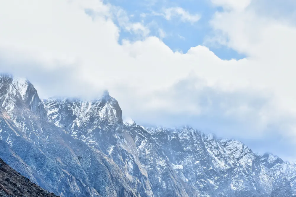 Majestic snow-covered mountains of Kedarnath, India, under a cloudy sky, showcasing natural beauty and rugged terrain.