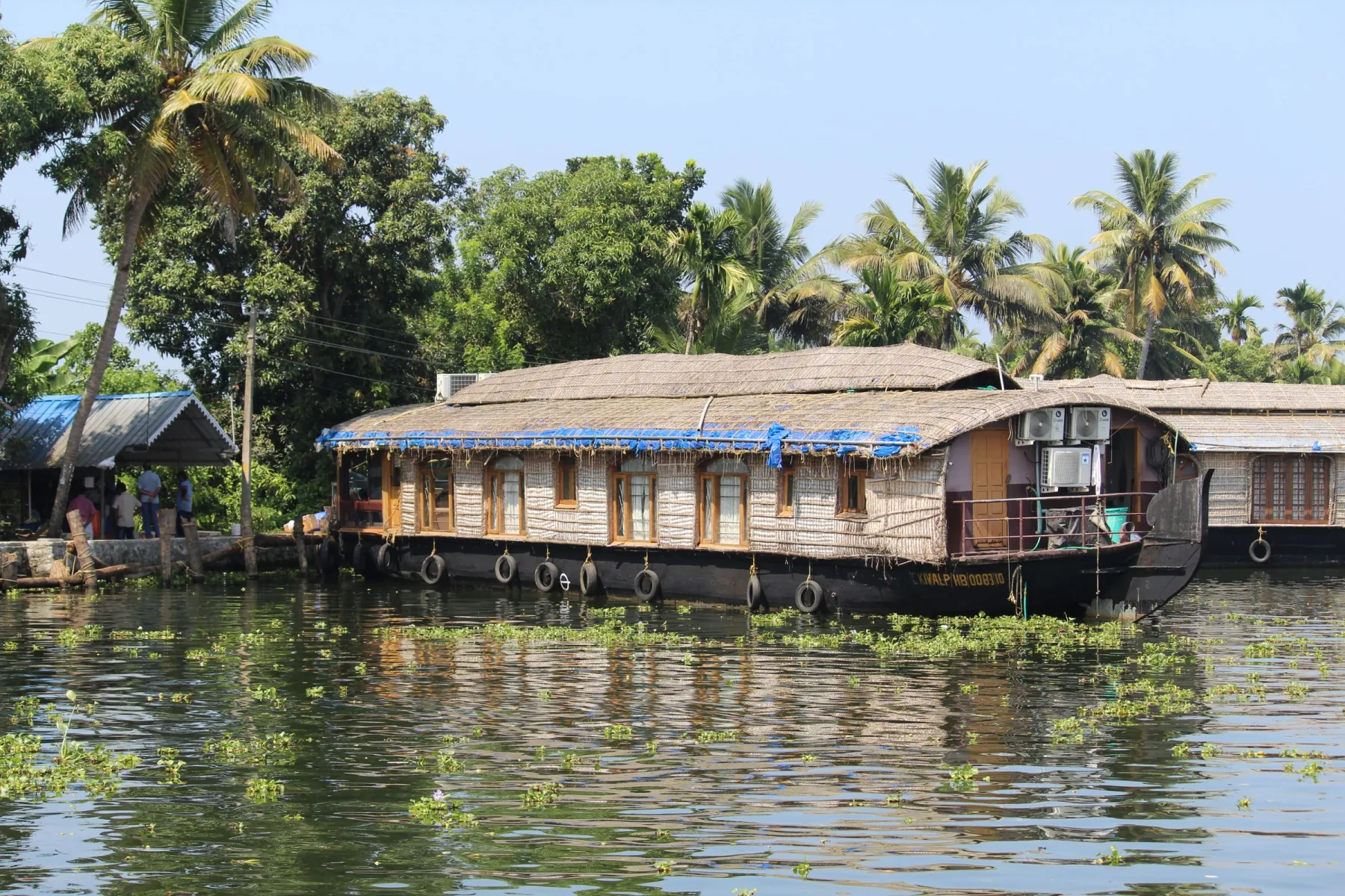 Scenic houseboat in Alappuzha, Kerala, surrounded by lush palm trees. Perfect tropical travel destination.