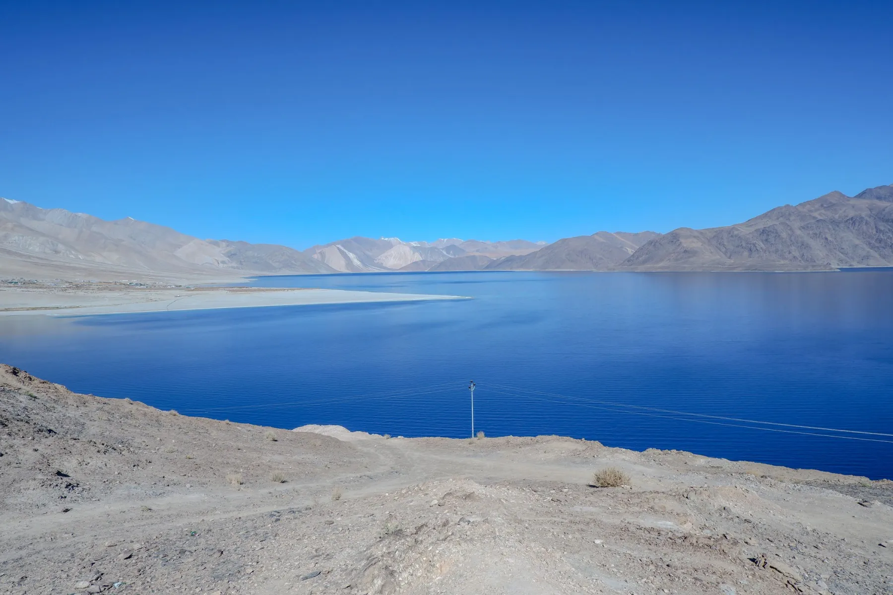 Captivating view of Pangong Lake with clear blue skies and mountain backdrop.
