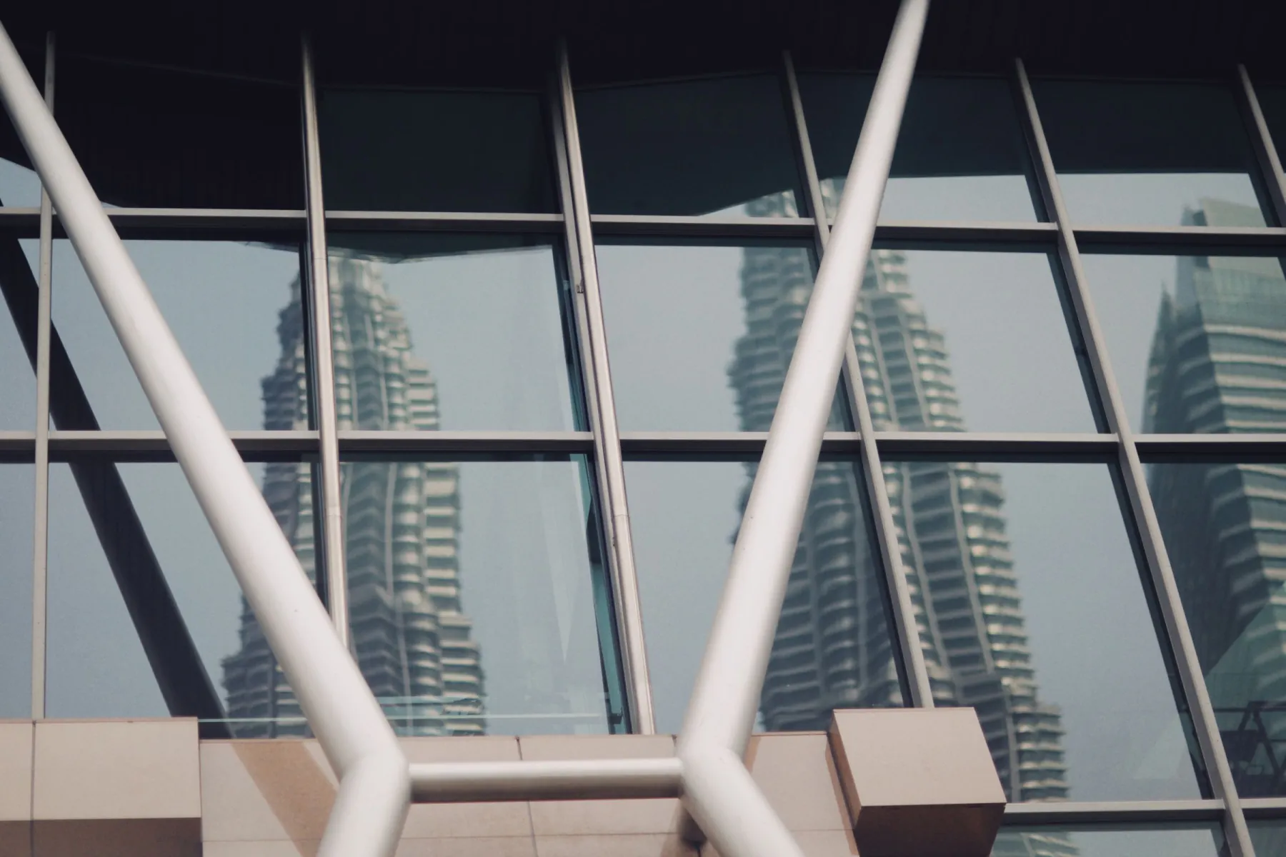 Reflection of Petronas Towers in a modern glass building in Kuala Lumpur, Malaysia.