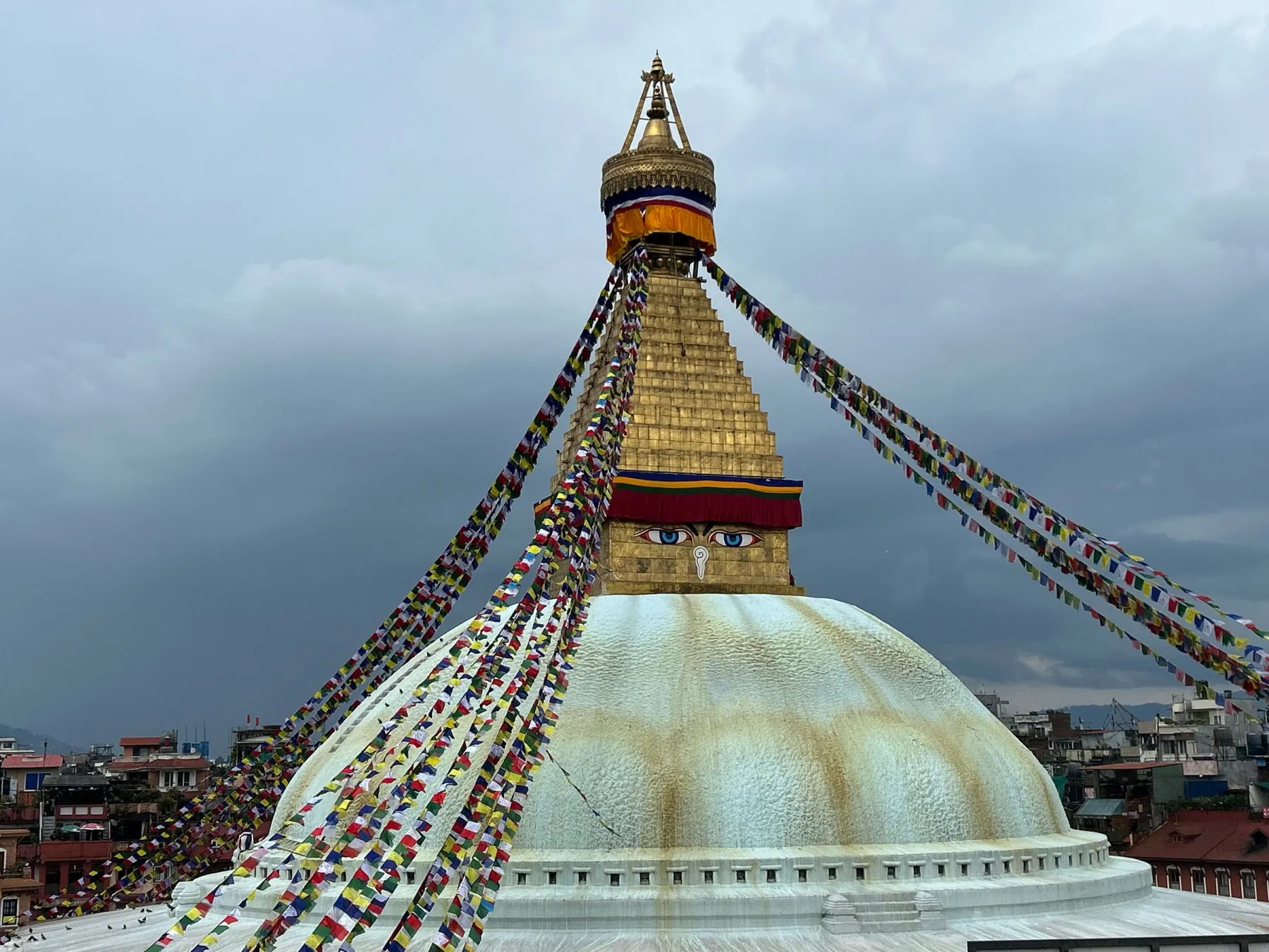 Iconic Boudhanath Stupa with prayer flags in Kathmandu, Nepal on a cloudy day.
