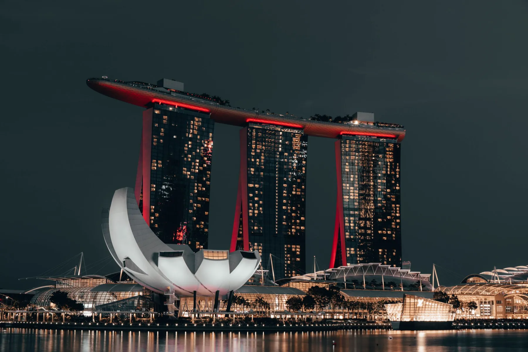 Dramatic night view of Marina Bay Sands, Singapore, with glowing cityscape and reflection.