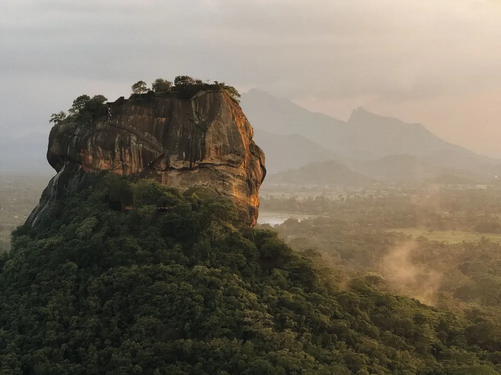 Stunning aerial view of Sigiriya Rock, lush landscape, and distant mountains in Sri Lanka.