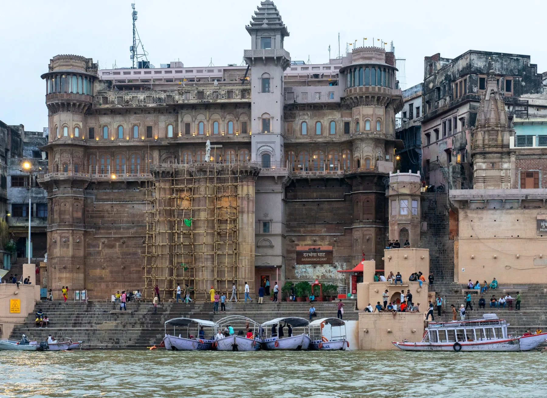 Historic building at Varanasi Ghat with boats on the Ganges, capturing cultural essence.