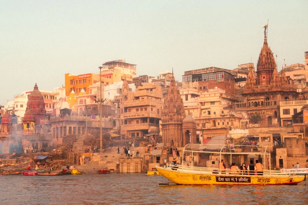Colorful temples and boats on the Ganges River in Varanasi during the day.