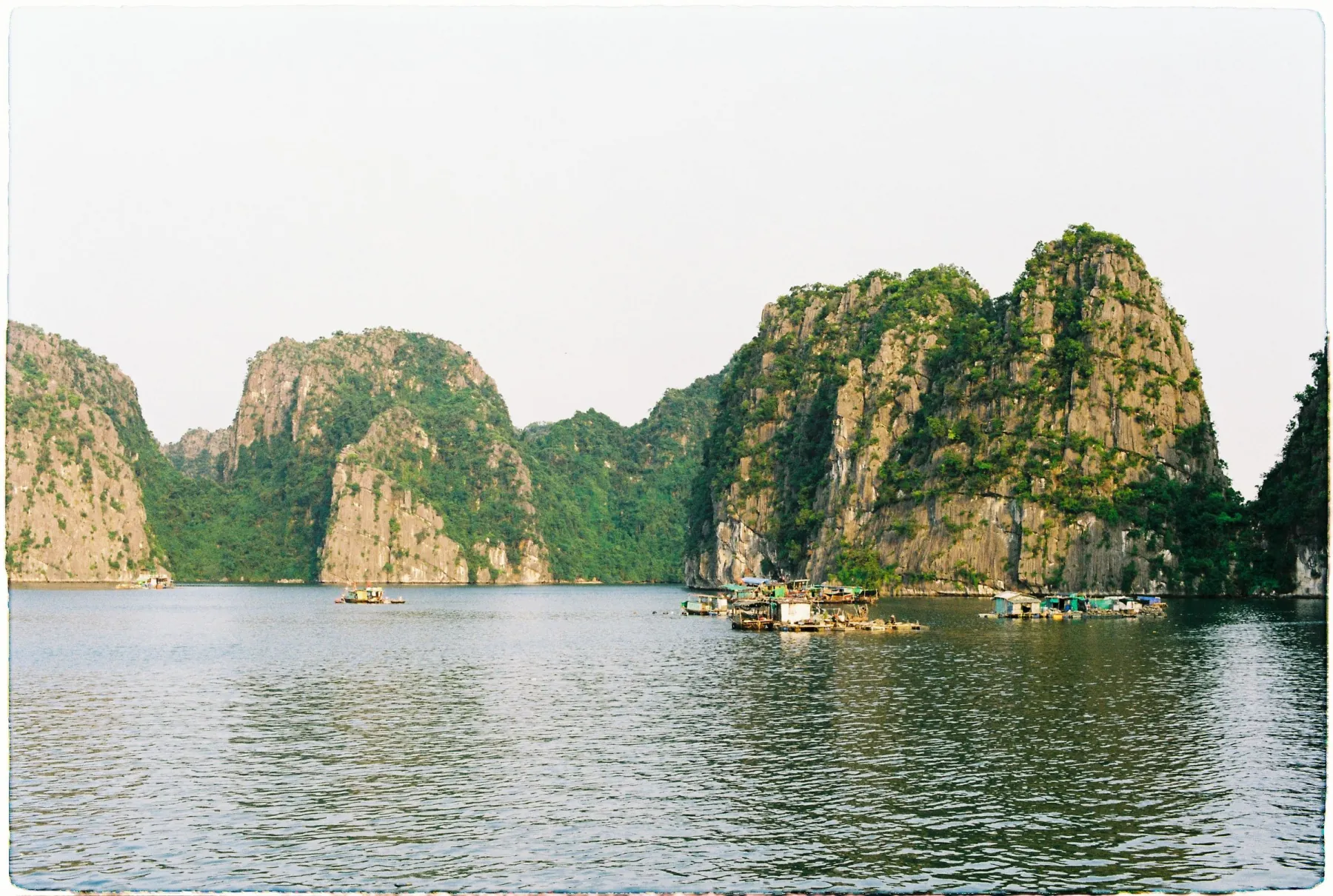 Picturesque view of limestone islands and floating villages in Ha Long Bay, Vietnam at daytime.
